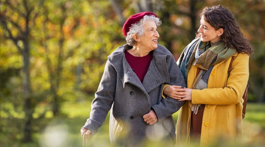 giovane donna e signora anziana sorridenti passeggiano in un parco