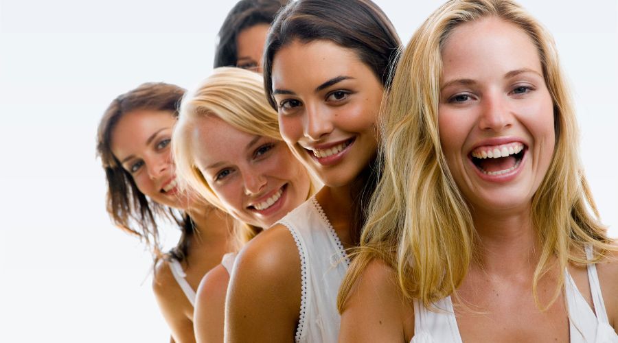 Cinque giovani donne sorridenti, a mezzobusto, su sfondo bianco